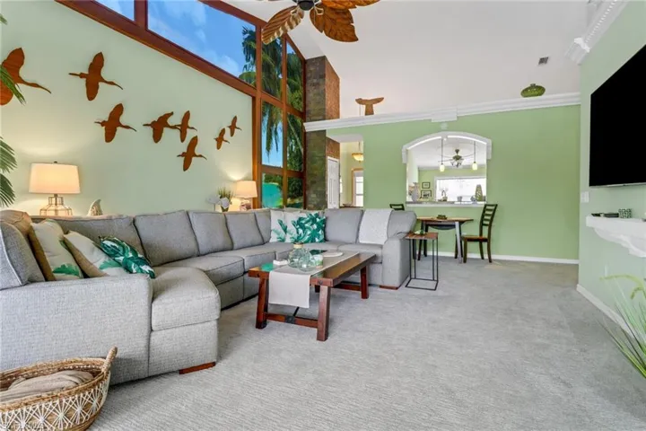 Carpeted living room with high vaulted ceiling and a ceiling fan