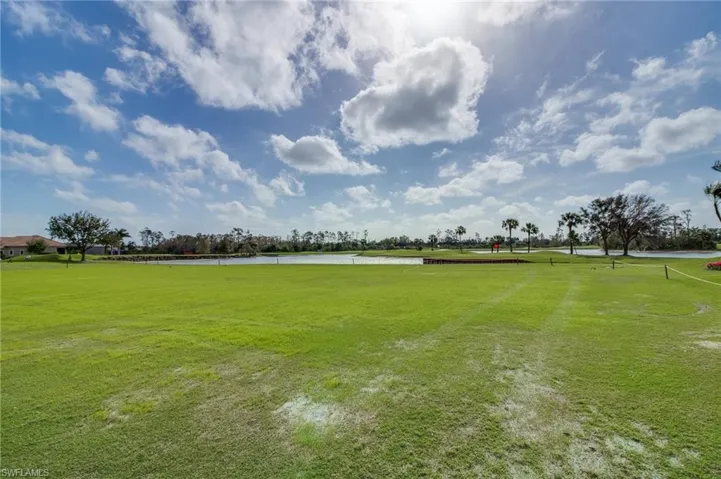 View of community with golf course view, a water view, and a yard