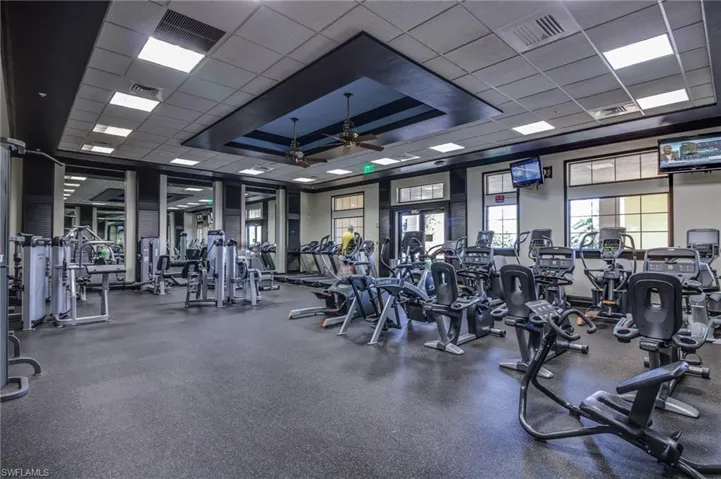Exercise room featuring a paneled ceiling, ceiling fan, and a raised ceiling