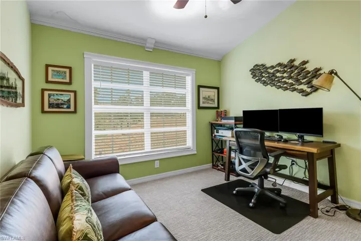 Office area featuring carpet floors, a ceiling fan, and crown molding