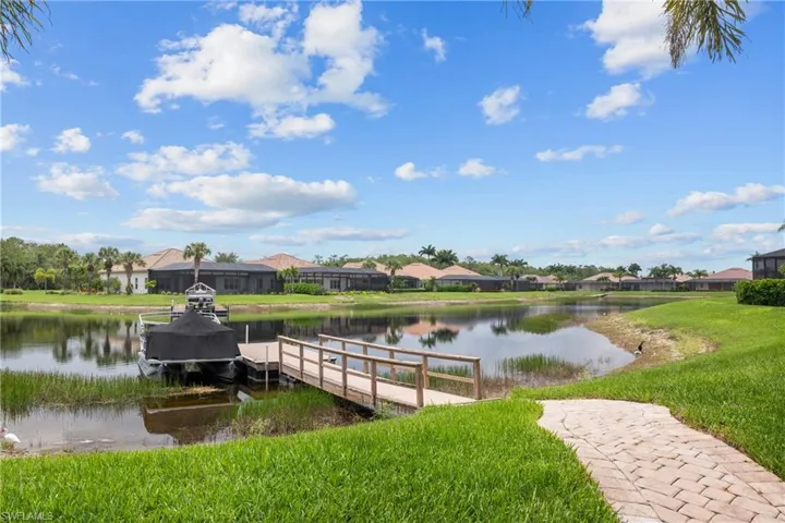 Private dock with a water view, a residential view, and a lawn