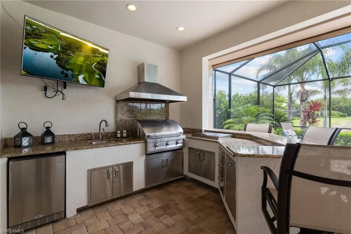View of patio featuring glass enclosure, a sunroom, and exterior kitchen