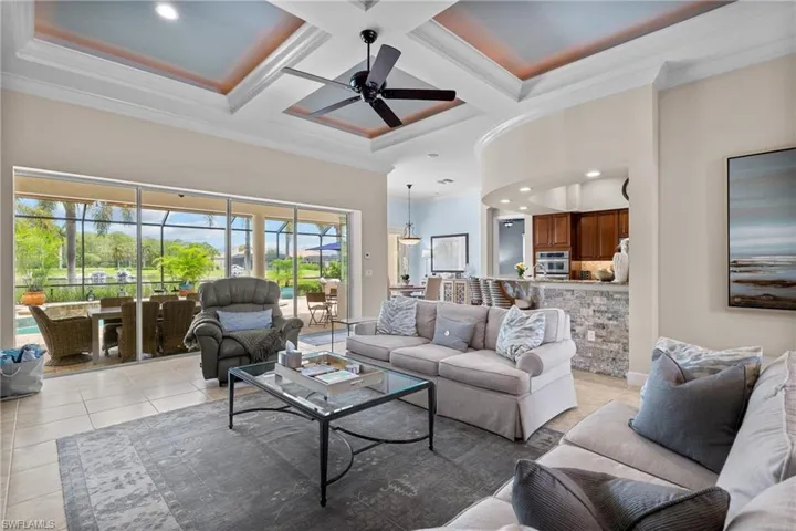 Living room with coffered ceiling, a ceiling fan, ornamental molding, recessed lighting, and light tile patterned floors