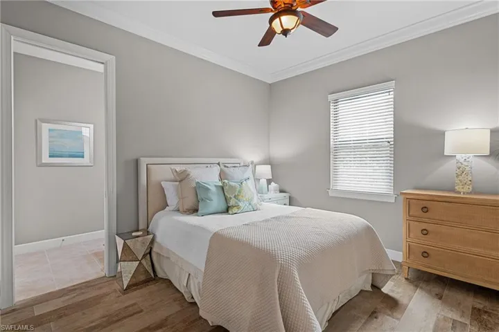 Bedroom featuring ornamental molding, light wood-style flooring, and a ceiling fan