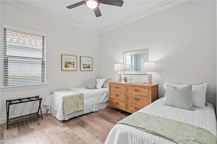 Bedroom with crown molding, light wood-type flooring, multiple windows, and ceiling fan