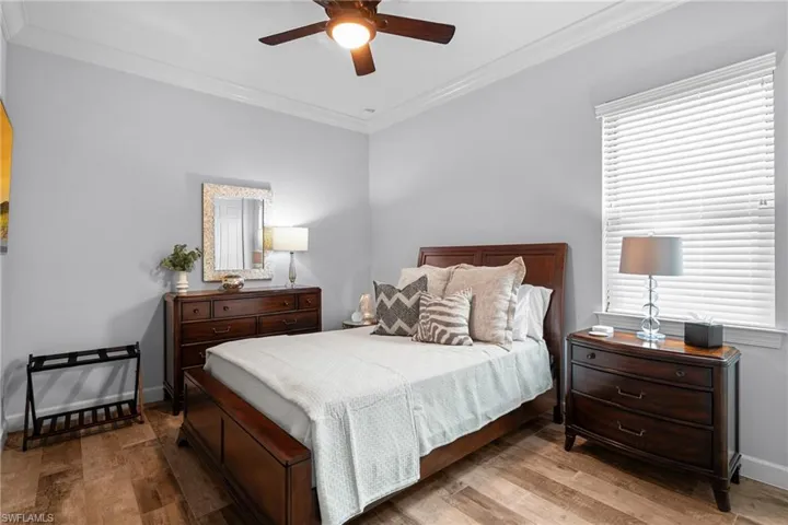 Bedroom with hardwood / wood-style floors, crown molding, and a ceiling fan