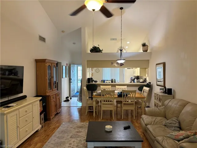 Living room featuring high vaulted ceiling, ceiling fan, and luxury vinyl tile flooring.