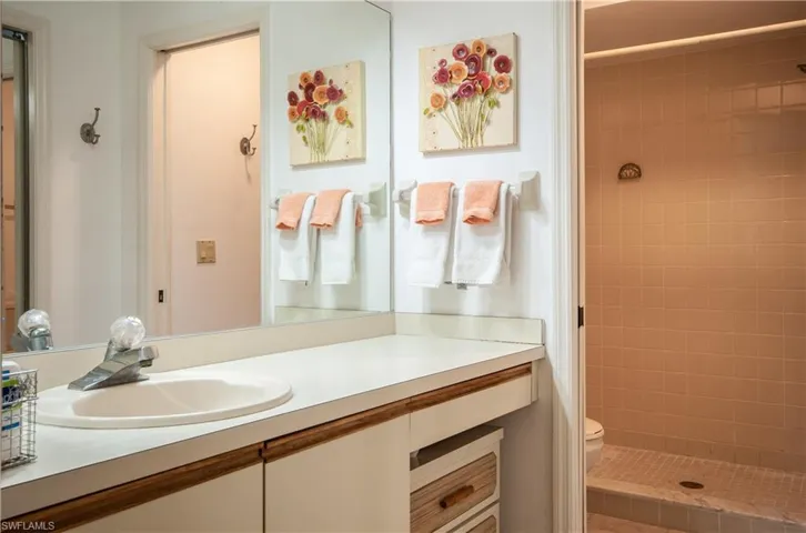 Bathroom featuring a tile shower, toilet, and large vanity