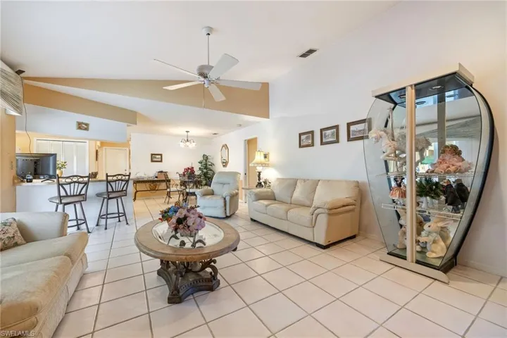 Living room featuring a ceiling fan, lofted ceiling, a chandelier, and light tile patterned flooring