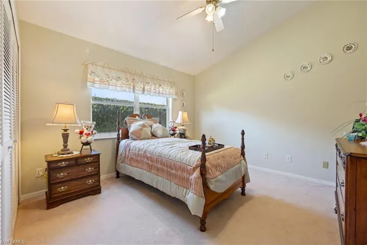 Guest Bedroom with light carpet, vaulted ceiling, and a ceiling fan
