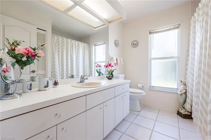 Guest Full bathroom featuring vanity, light tile patterned flooring, and curtained shower