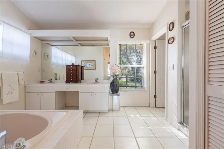 Primary bathroom, full bath with a closet, vanity, healthy amount of natural light, and light tile patterned flooring
