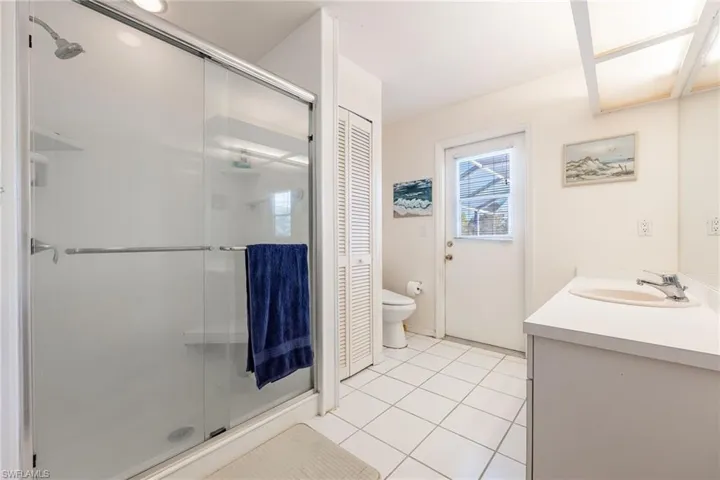 Guest Bathroom featuring a closet, vanity, light tile patterned floors, and a stall shower