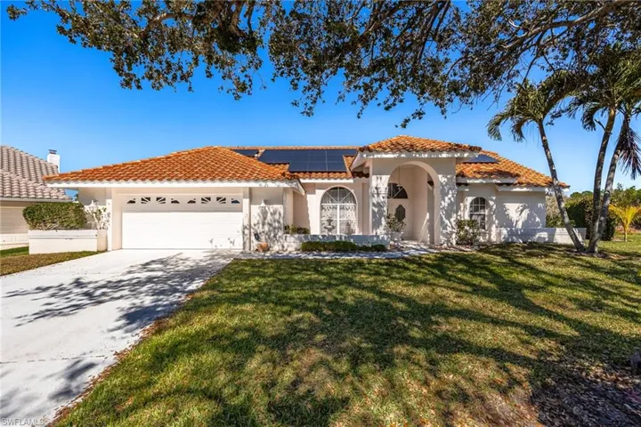 Mediterranean / spanish-style home featuring stucco siding, roof mounted solar panels, driveway, a garage, and a front yard