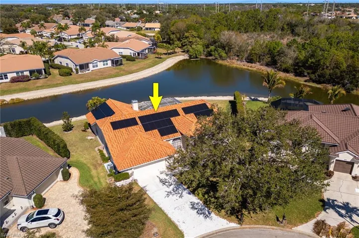 Aerial view of residential area with a nearby body of water and a tree filled landscape