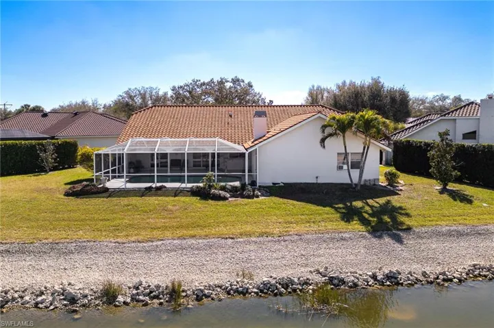 Rear view of house featuring a tiled roof, a lanai, an outdoor pool, and a yard