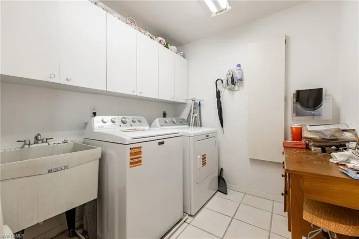 Laundry area featuring independent washer and dryer, cabinet space, and light tile patterned floors