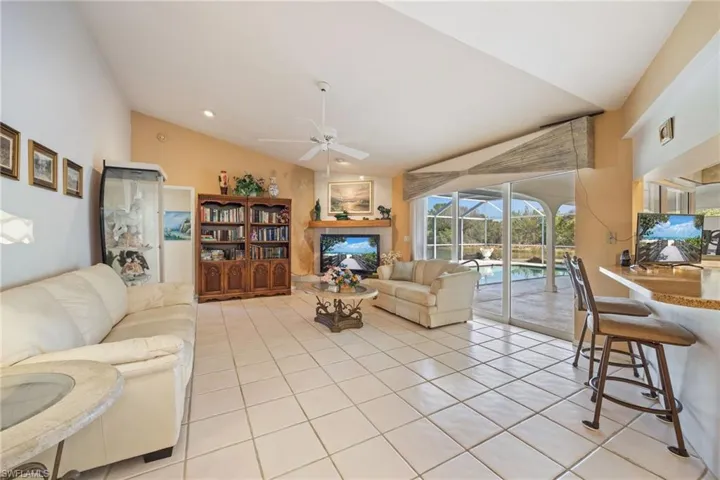 Living area with vaulted ceiling, a ceiling fan, light tile patterned floors, and a sunroom