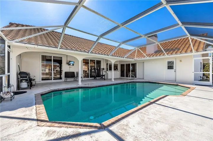 Swimming pool with a patio area, a sunroom, glass enclosure, and a grill