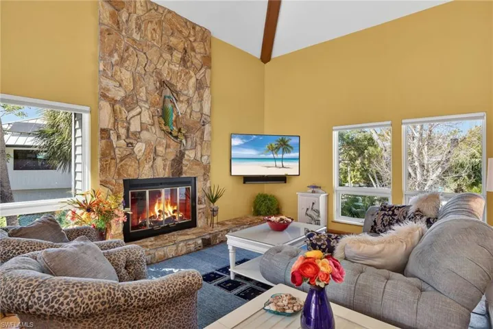 Living room featuring high vaulted ceiling and a stone fireplace
