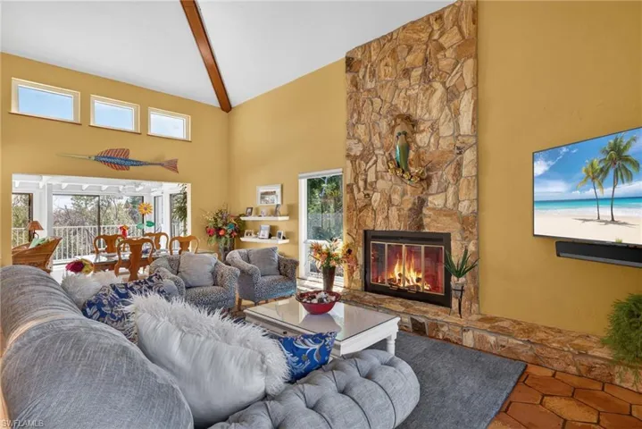 Living room with a fireplace, high vaulted ceiling, and beam ceiling