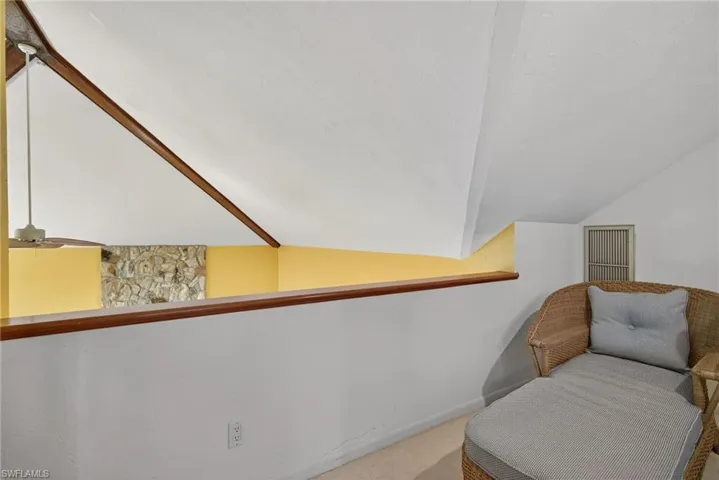Living area featuring vaulted ceiling, a textured ceiling, and carpet flooring