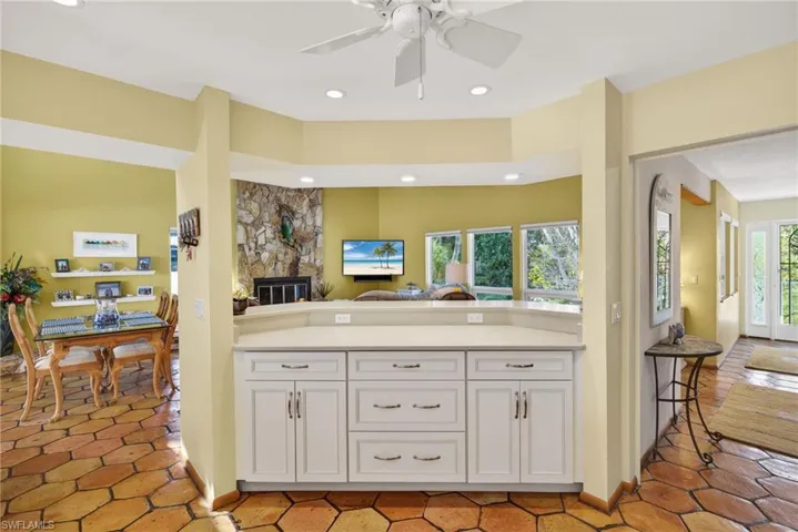 Kitchen with open floor plan, white cabinetry, recessed lighting, a fireplace, and ceiling fan
