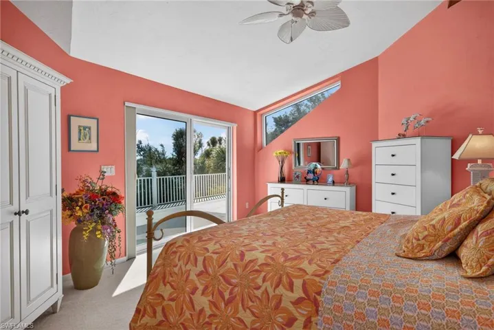 Primary Bedroom featuring access to exterior, light carpet, and a ceiling fan