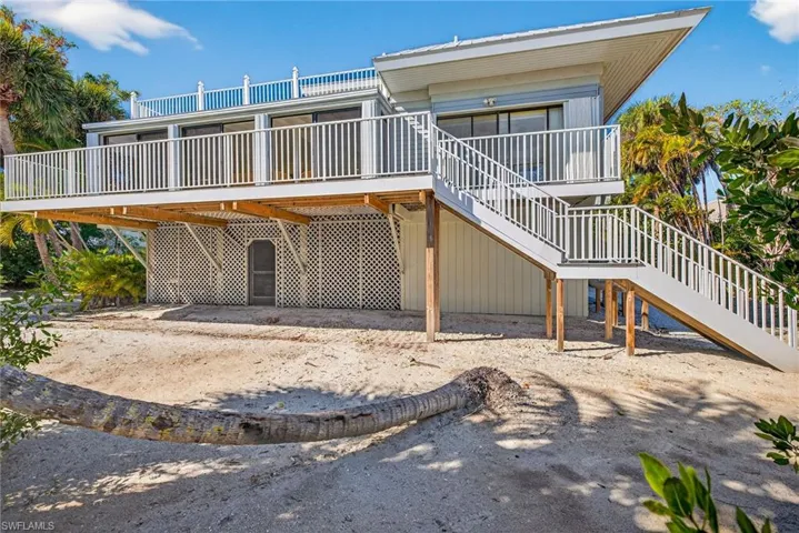 Rear view of property featuring stairway, a deck, and a carport
