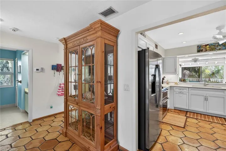 Kitchen with appliances with stainless steel finishes, light tile patterned floors, a ceiling fan, and white cabinetry