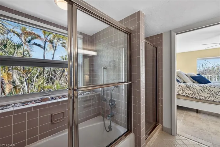 Bathroom with enclosed tub / shower combo, ensuite bathroom, and light tile patterned floors