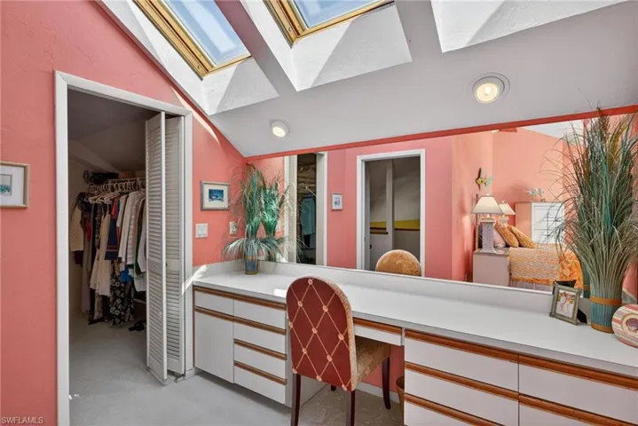 Primary Bedroom featuring lofted ceiling, a walk in closet, a skylight, connected bathroom, and vanity