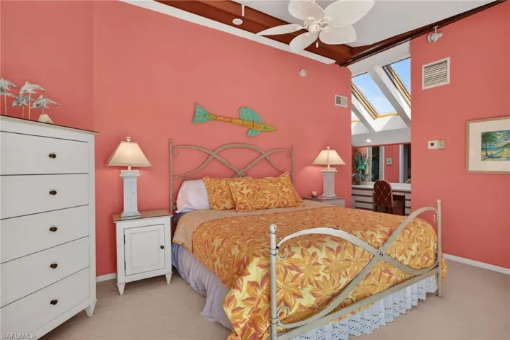 Primary Bedroom with a skylight, a ceiling fan, carpet flooring, and a towering ceiling