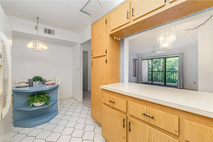 Kitchen with a chandelier, light countertops, open shelves, hanging light fixtures, and freestanding refrigerator