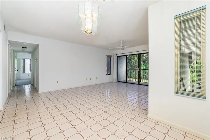 Living room featuring light flooring, a ceiling fan, and a chandelier