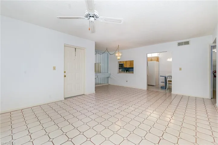 Unfurnished living room featuring tile patterned floors, ceiling fan, and a chandelier