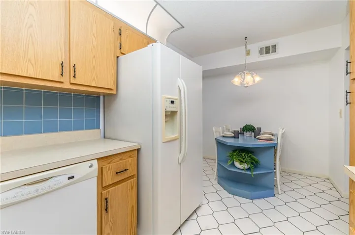 Kitchen featuring white appliances, tasteful backsplash, light countertops, open shelves, and a chandelier