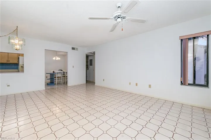 Living room with tile patterned floors, a chandelier, and ceiling fan