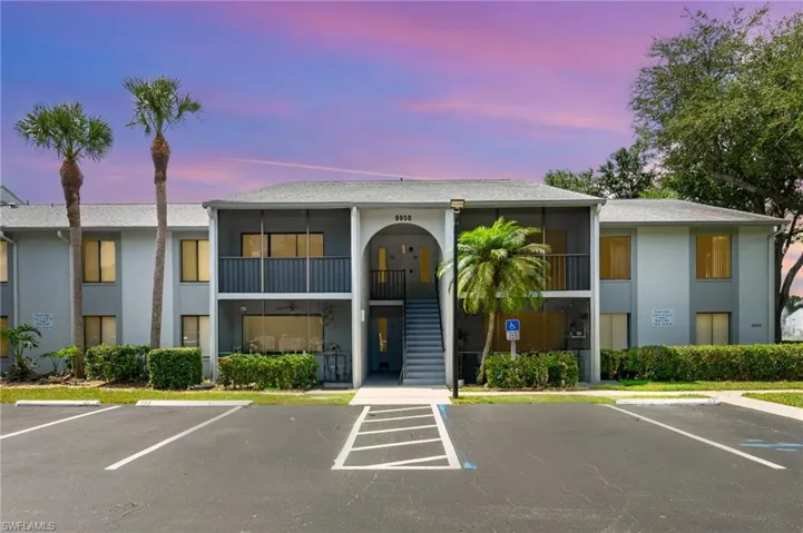 View of property featuring stairway and uncovered parking.  Unit #12 is on the second floor, right side.