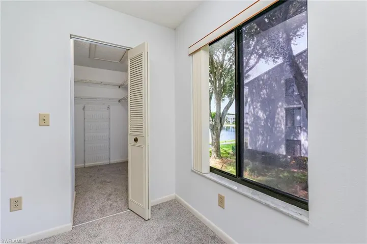 Unfurnished bedroom featuring carpet, a water view, and a walk in closet