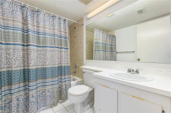Bathroom with vanity, tile patterned flooring, and shower / bathtub combination with curtain