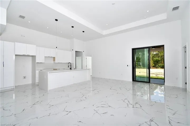 Kitchen with white cabinetry, a kitchen island with sink, a high ceiling, and a raised ceiling