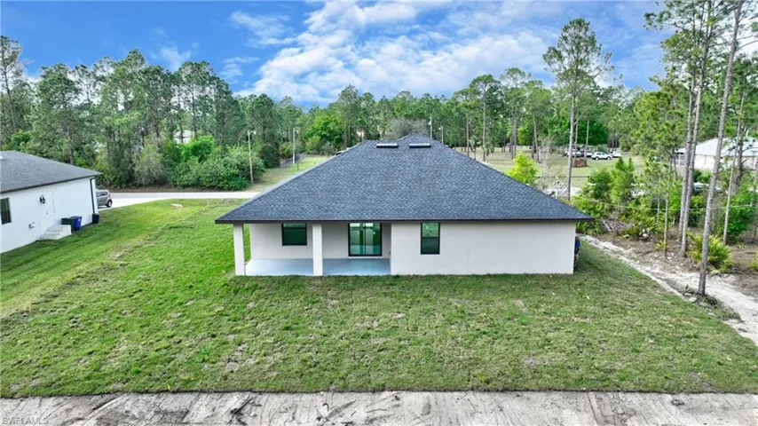 Rear view of house with a patio area and a lawn