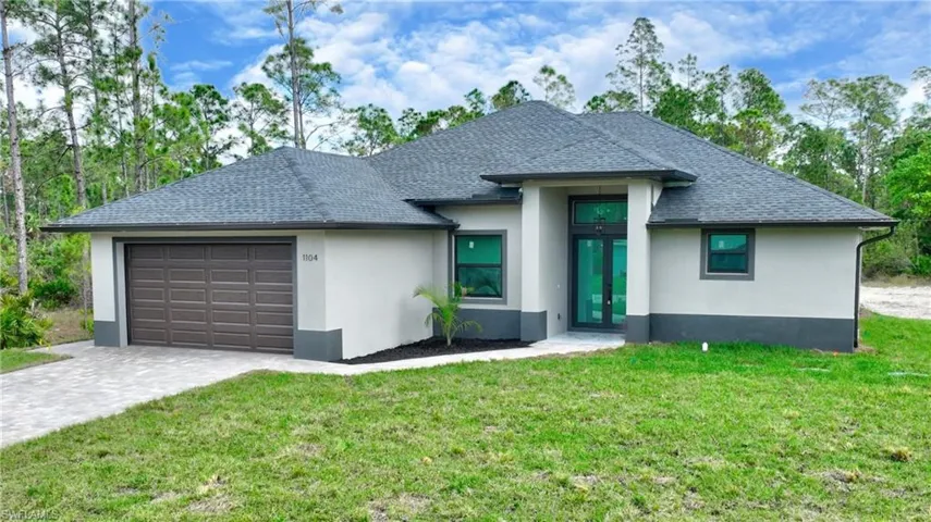 View of front of property featuring a garage, french doors, and a front yard