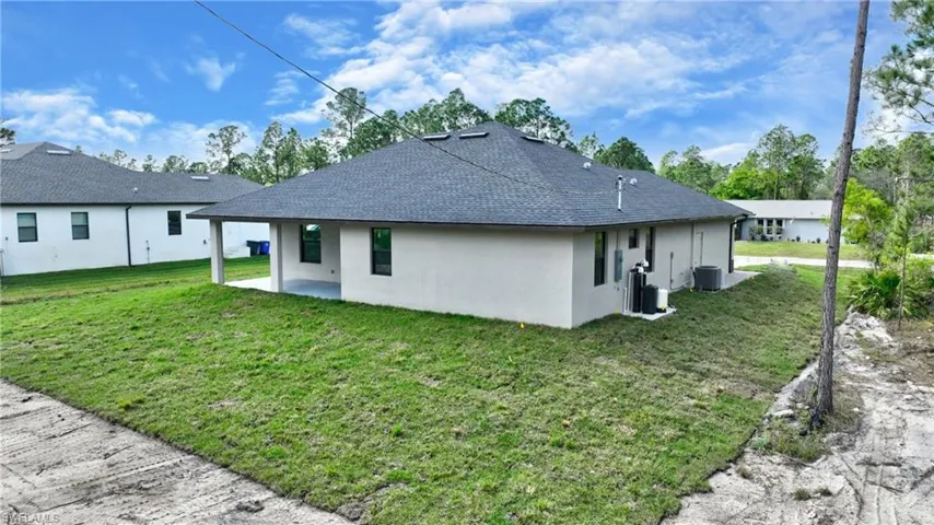 Back of property with central AC, a patio, and a lawn