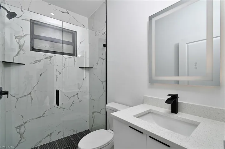 Bathroom featuring vanity, an enclosed shower, and toilet
