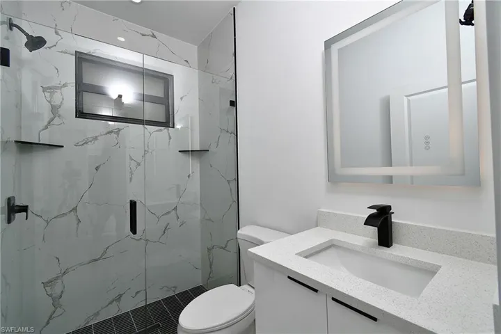 Bathroom with toilet, vanity, and an enclosed shower