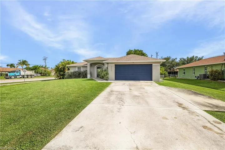 Single story home with stucco siding, concrete driveway, a front yard, a garage, and roof with shingles