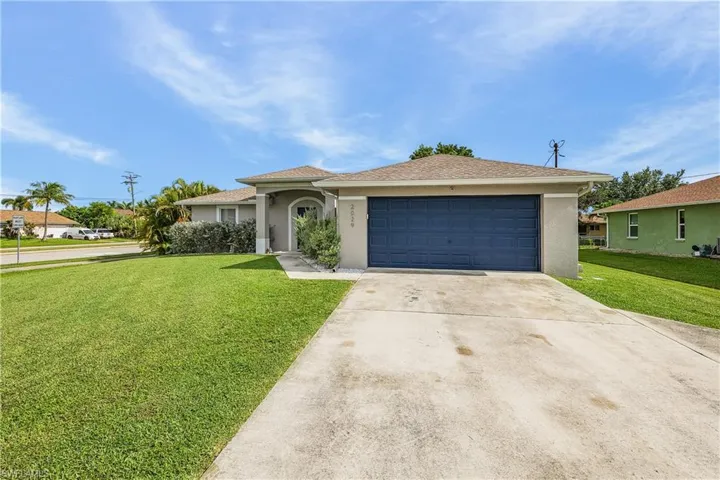 Ranch-style house featuring stucco siding, a garage, driveway, and a front lawn