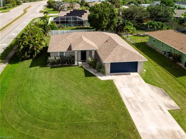 View of front of home with stucco siding, concrete driveway, a front lawn, and a garage